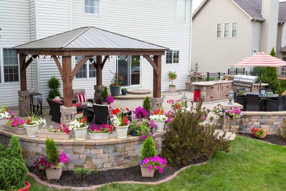 Cedar gazebo with a standing-seam metal roof over a paver patio with seating and landscaping