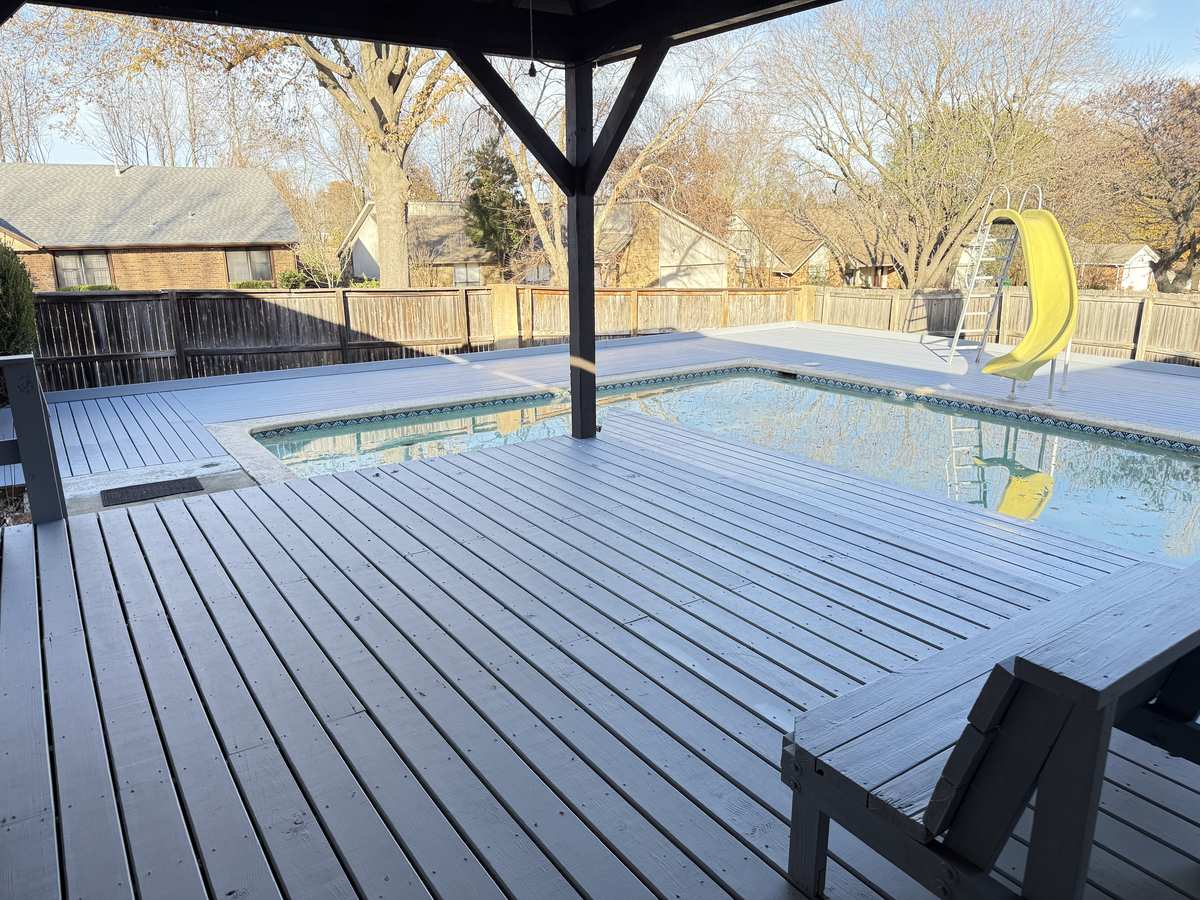 Grey composite pool deck wrapping an in-ground pool