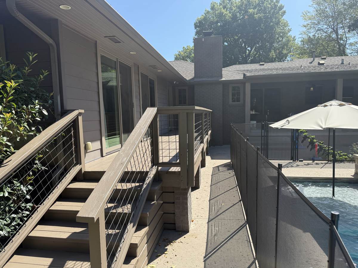 Composite stairs with black cable railing beside a pool