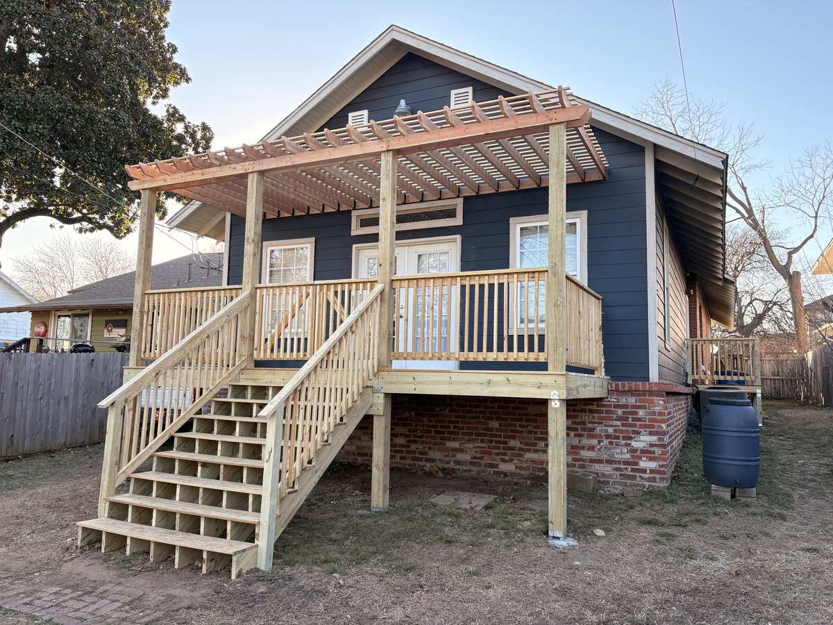 Two-story wood deck with pergola, stairs, and privacy fence